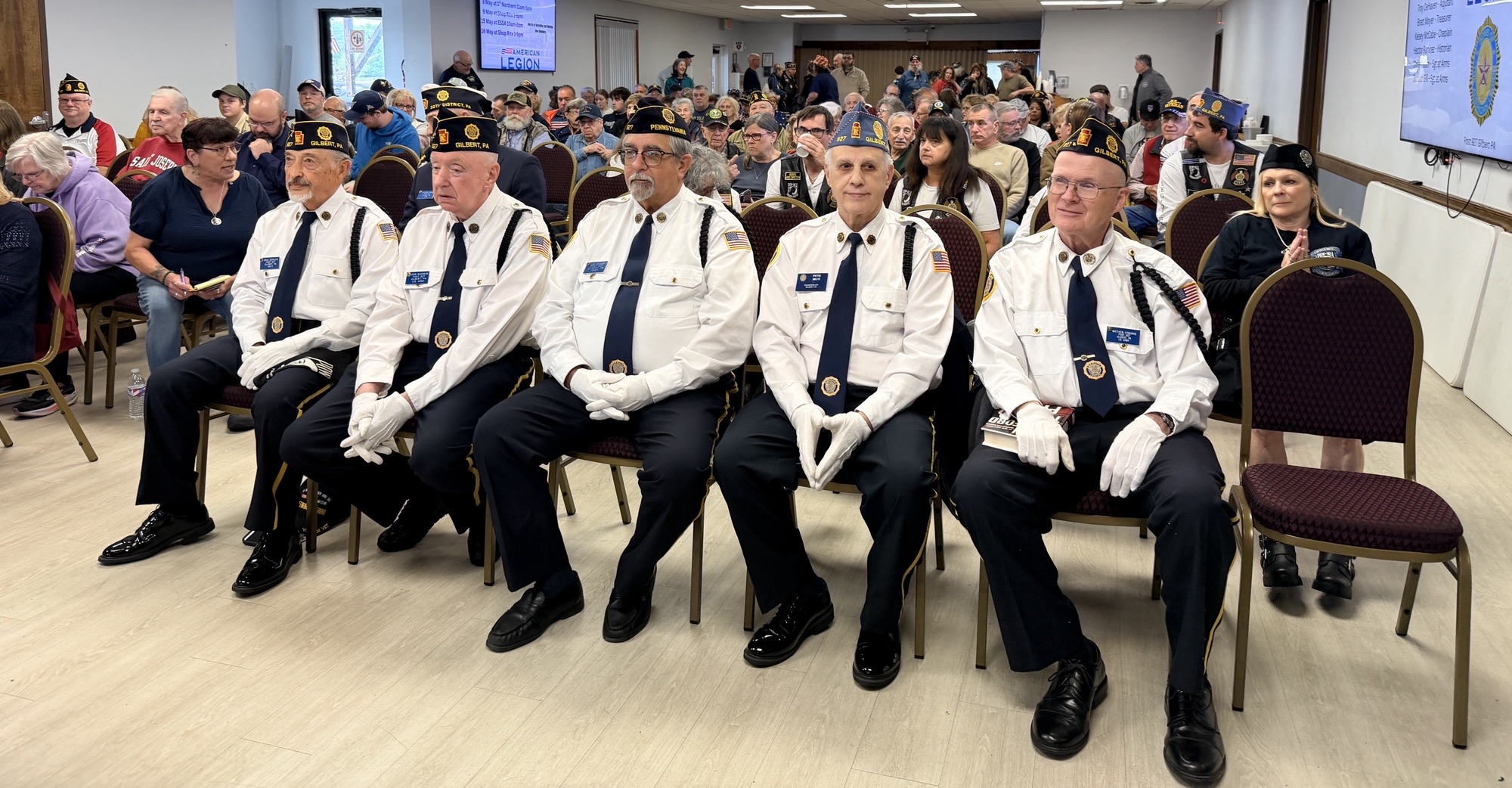 A group of Veterans sit in the front of a large crowd of nearly 100 people who have come to join to honor Memorial Day at the Gilbert American Legion Post 927.