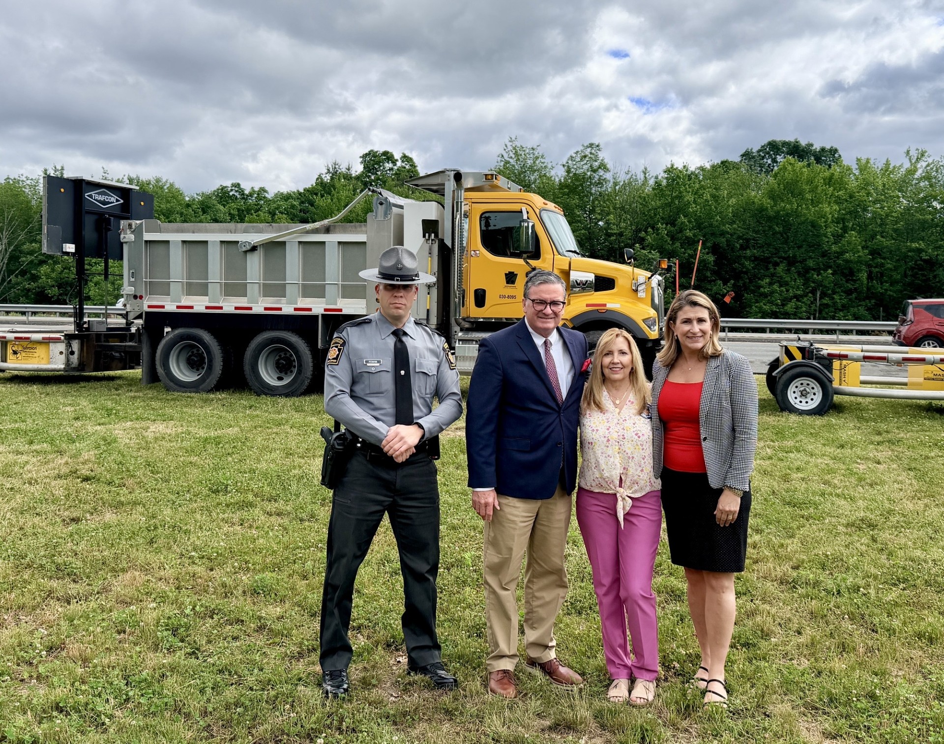 Sen. Rosemary Brown with PA State Trooper Anthony Petroski, PennDOT Secretary Mike Carroll, and Eileen Miller on Route 33 in Saylorsburg, Monroe County. They are standing in front of a PennDOT truck with the roadway in the background.
