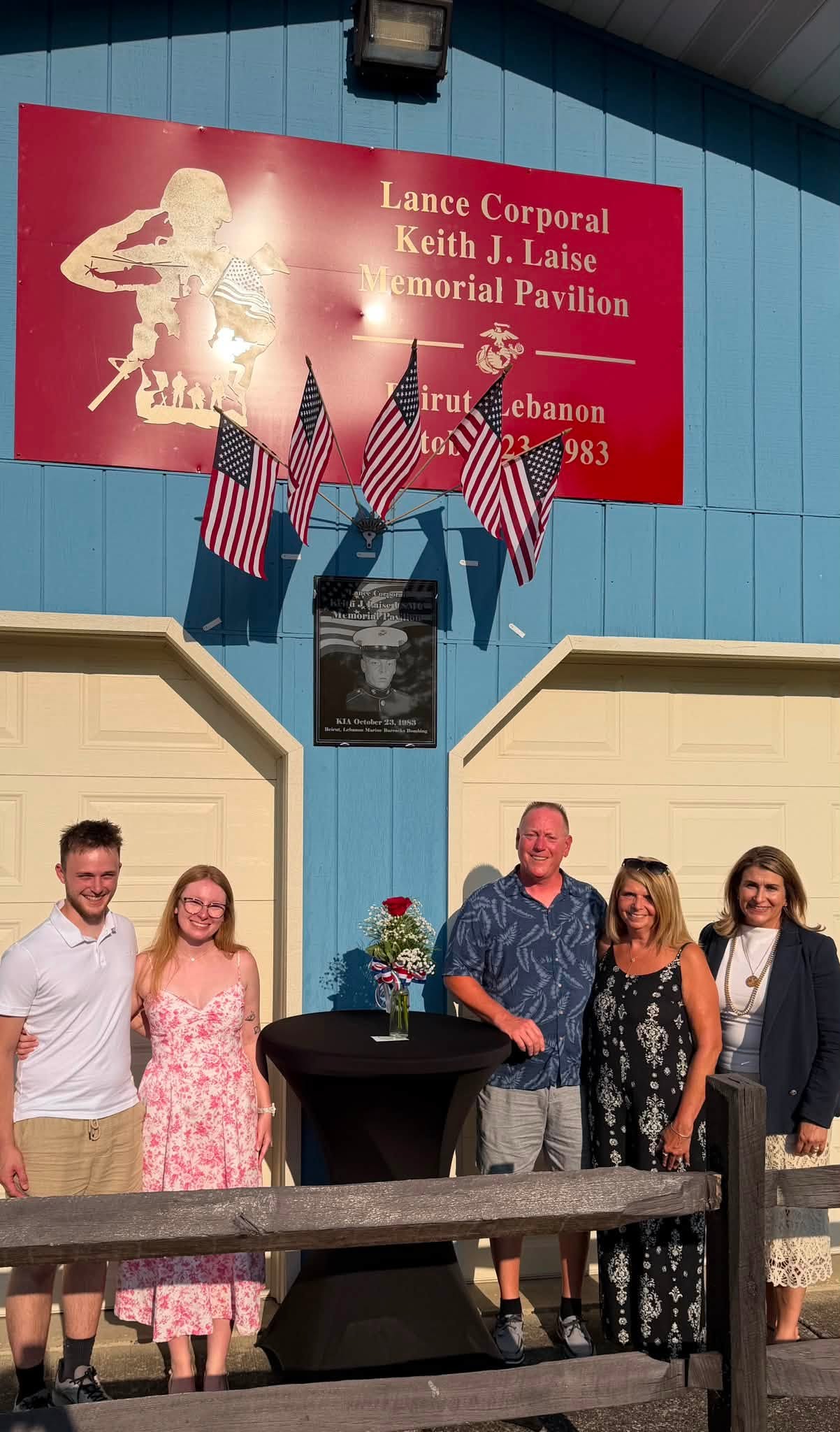 Sen. Brown with 4 people standing in front of a memorial sign for Lance Corporal Keith J. Laise.