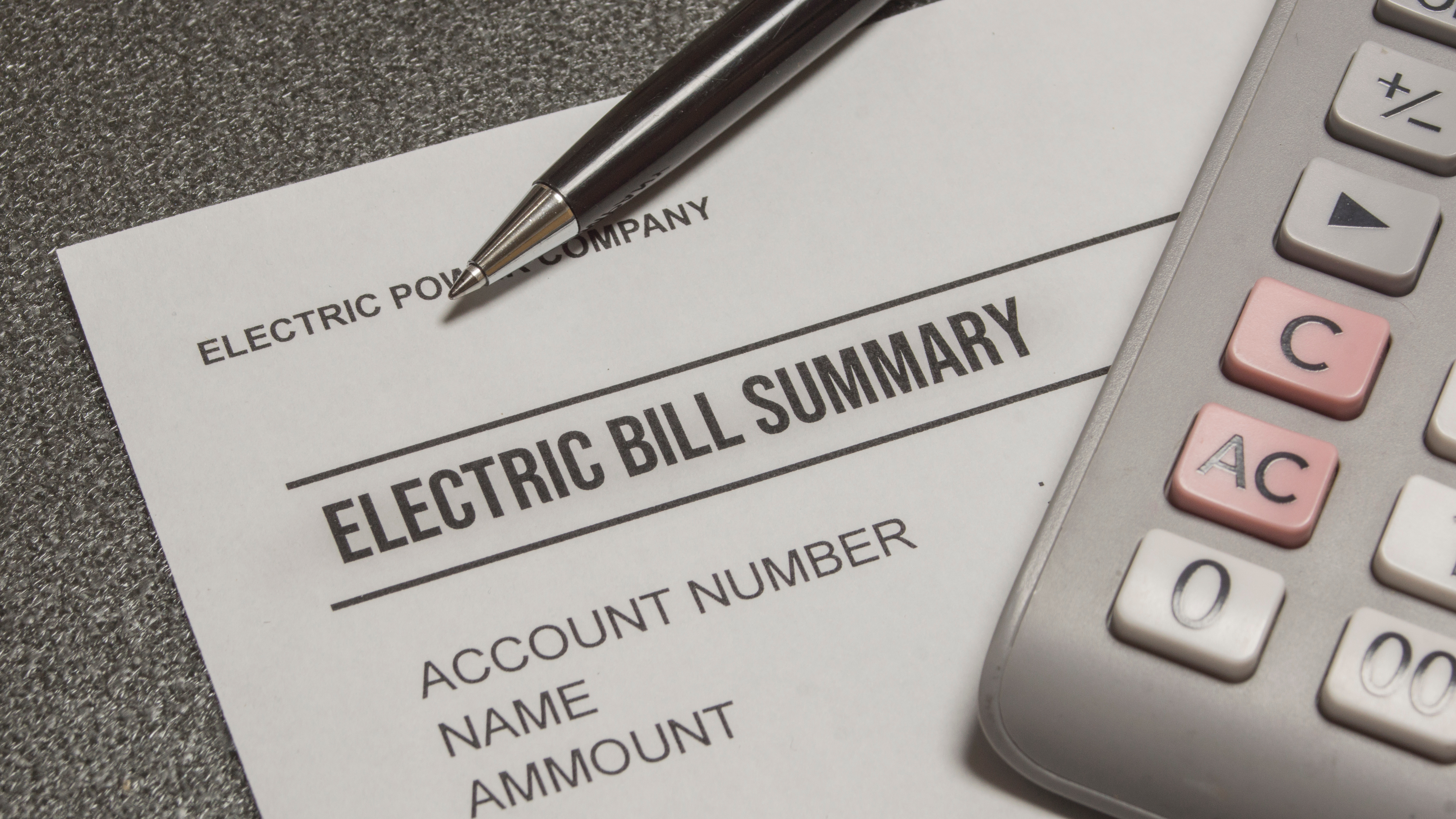 electric bill summary and a pen and a calculator